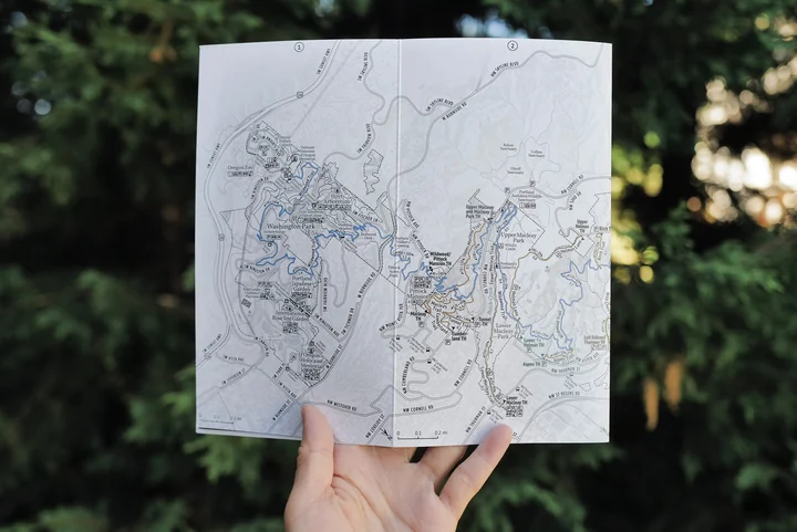 A hand holds the folded Forest Park Pocket Adventure Map.